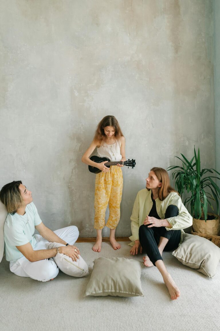 A family shares a musical moment as a child plays the ukulele, surrounded by parents in a cozy indoor setting.